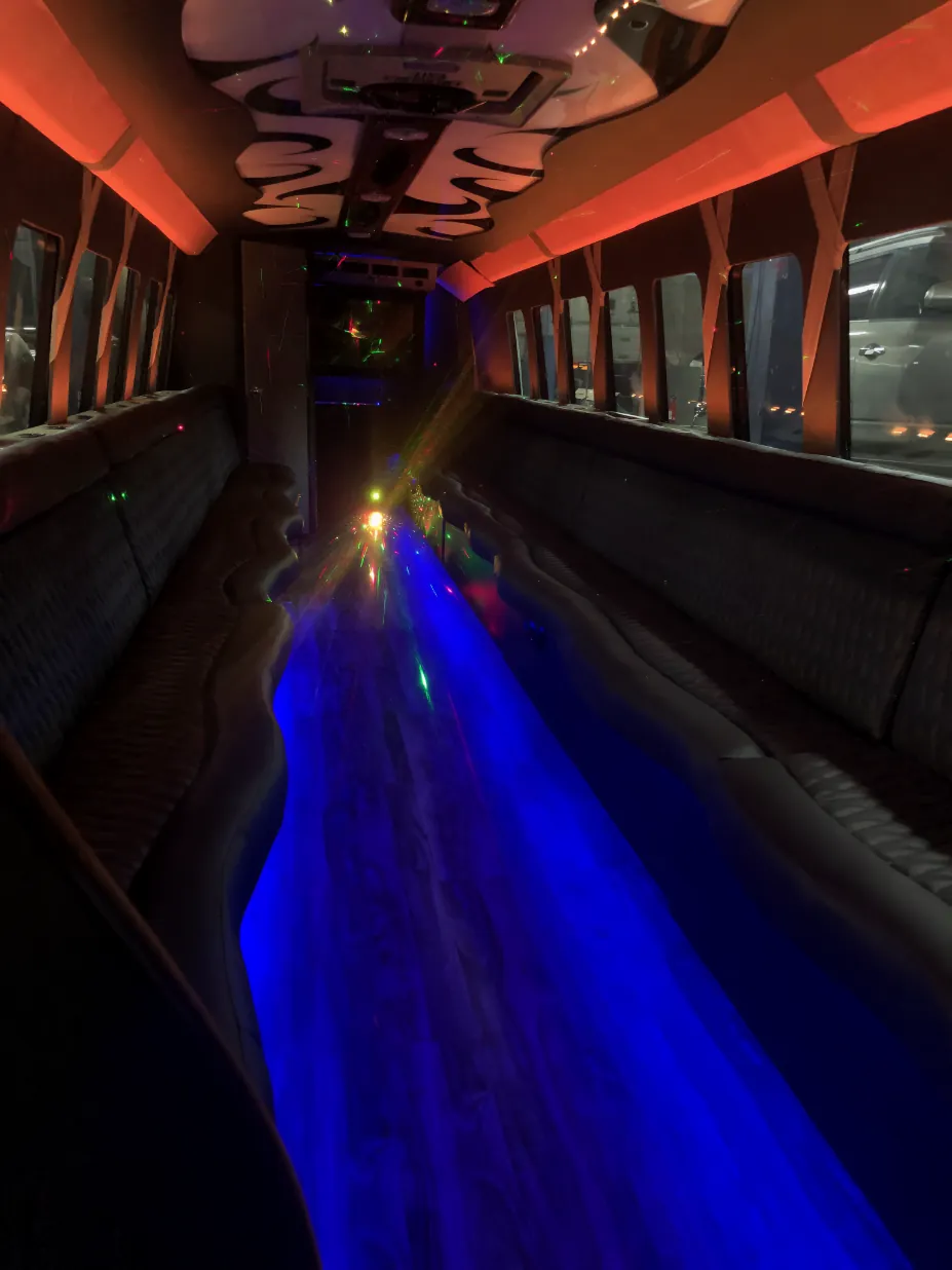 Interior of 40-passenger QTS party bus showing LED lighting and perimeter lounge seating for large group events in Dallas-Fort Worth