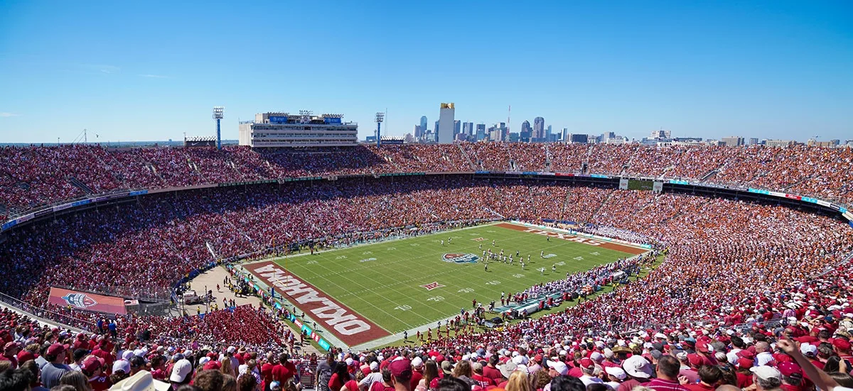 Cotton Bowl Stadium in Fair Park, Dallas, packed for the Red River Rivalry with the downtown skyline beyond — QTS Black Car & Limo transportation for September 2026 events