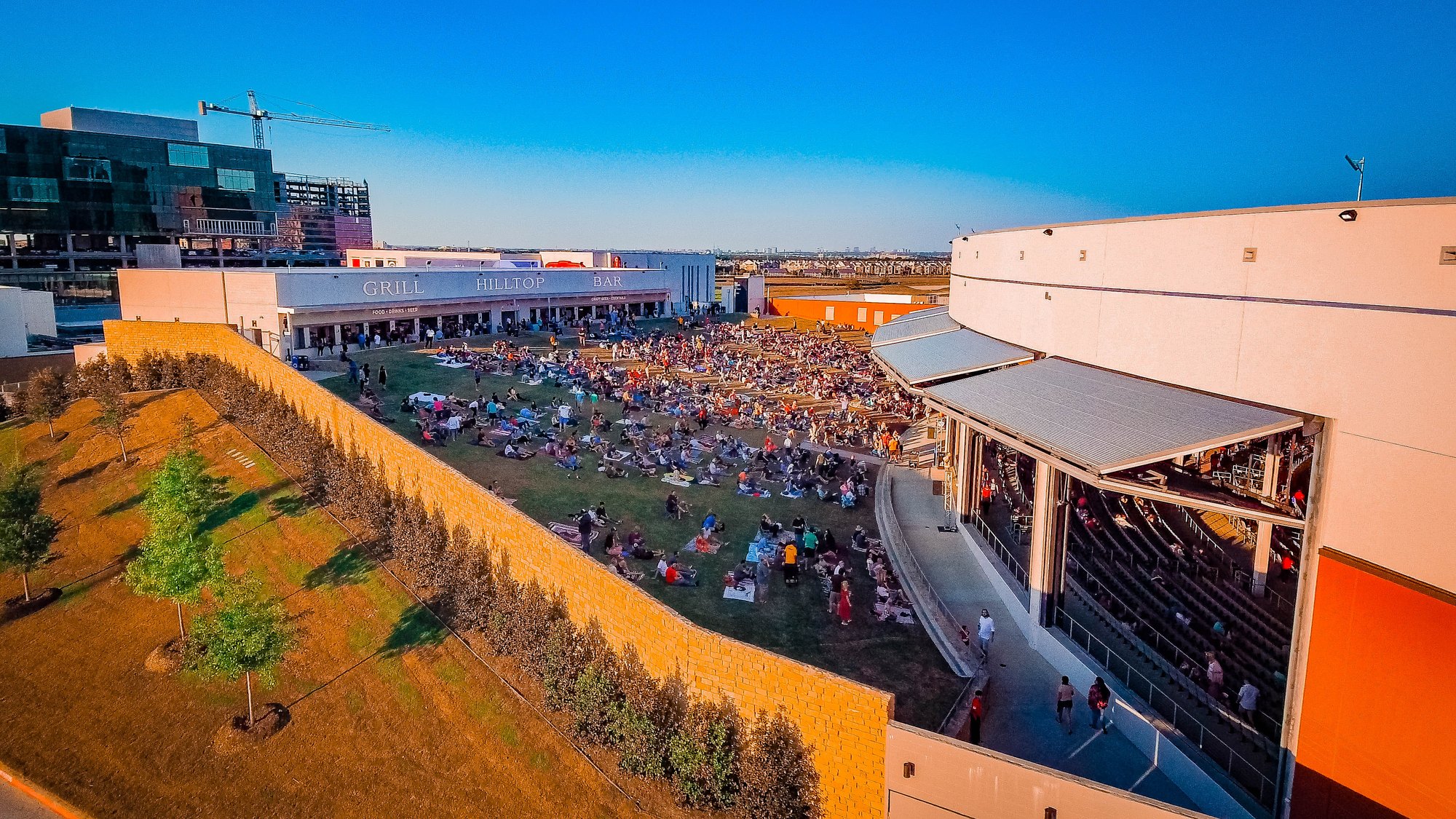 The lawn and covered seating at The Pavilion at Toyota Music Factory in Las Colinas, Irving, filling before a show — QTS Black Car & Limo transportation for September 2026 events
