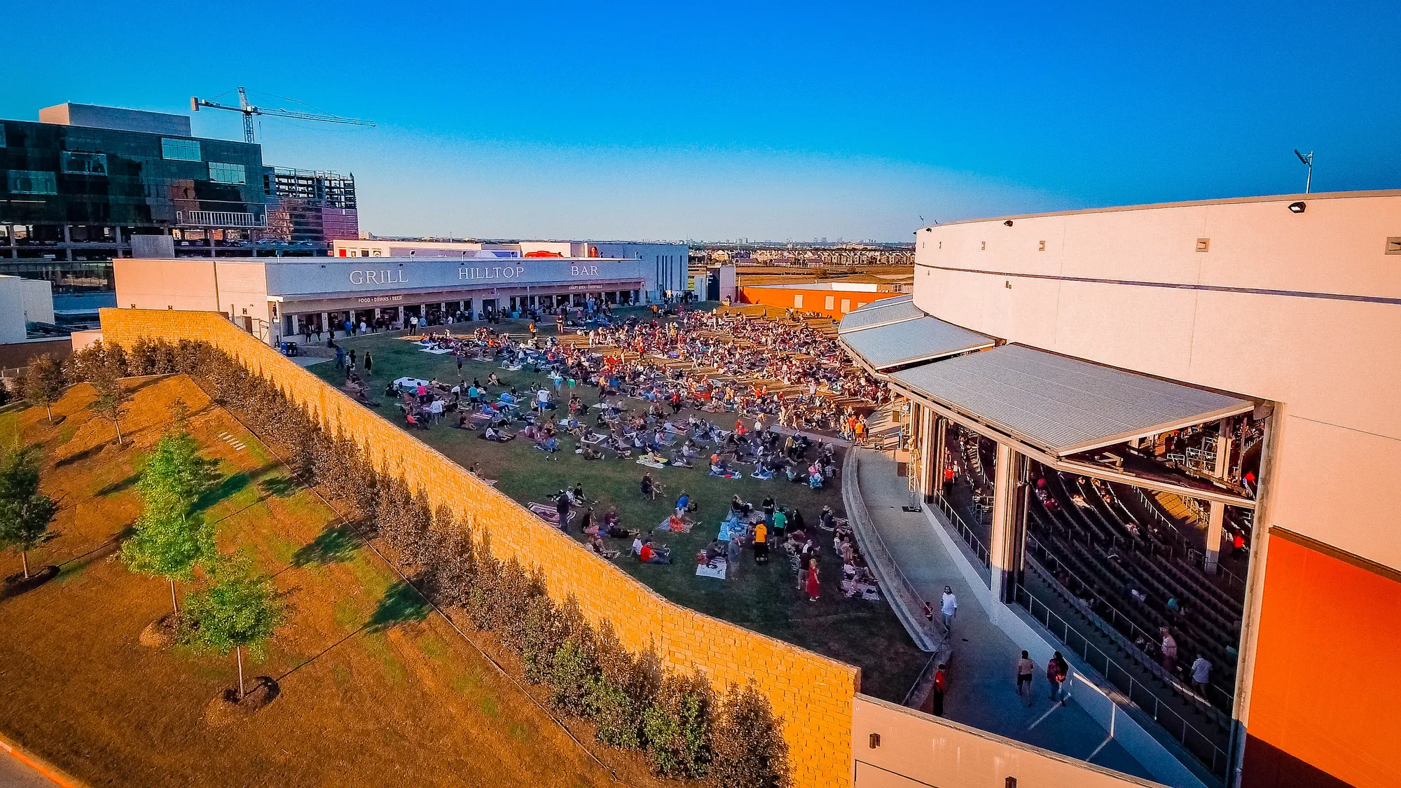 The lawn and covered seating at The Pavilion at Toyota Music Factory in Las Colinas, Irving, filling before a show — QTS Black Car & Limo transportation for September 2026 events